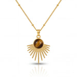Gold necklace with a sunburst pendant featuring a brown gemstone on a white background