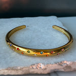 Aerina bracelet in rainbow star style, displayed on a white stone surface with warm lighting.