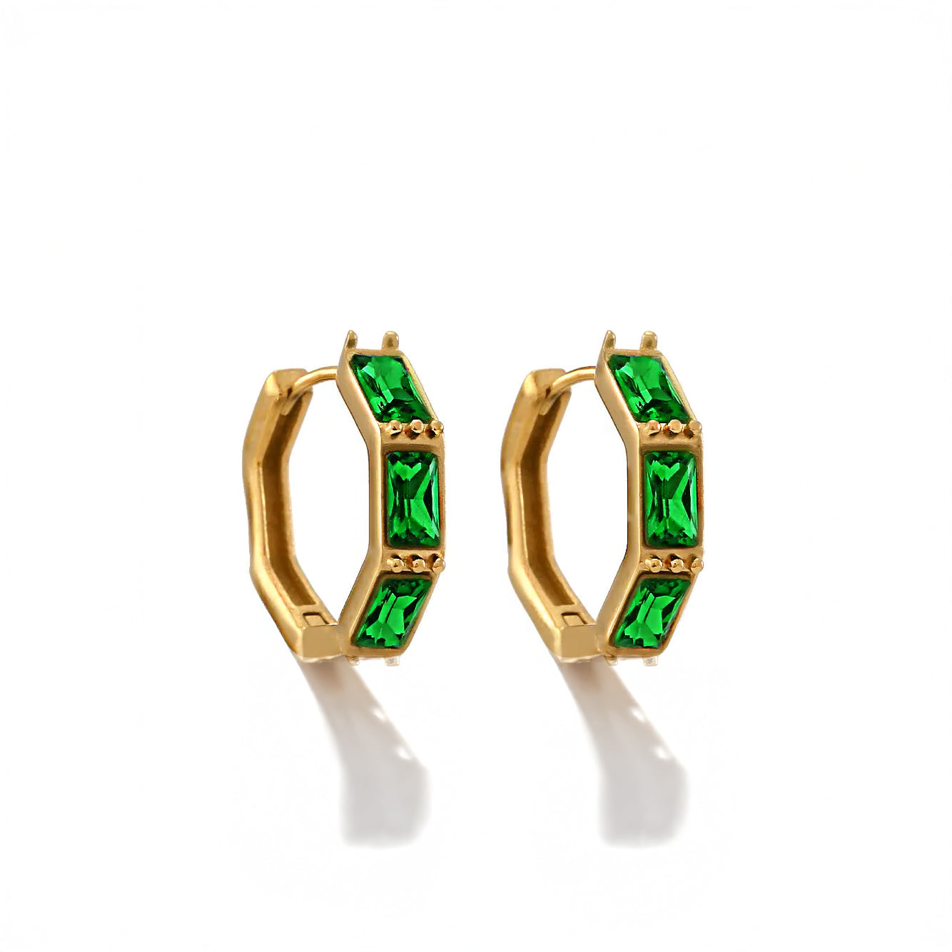 Close-up of gold hoop earrings with vibrant green and clear zircon stones on a soft neutral background.