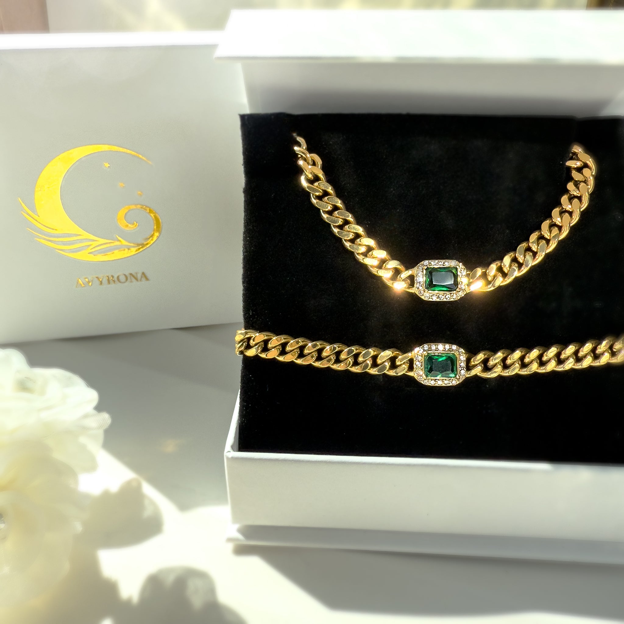 Gold chain necklace and bracelet set with emerald-green accents, displayed in a white Avyrona jewelry box — a perfect gift for her.
