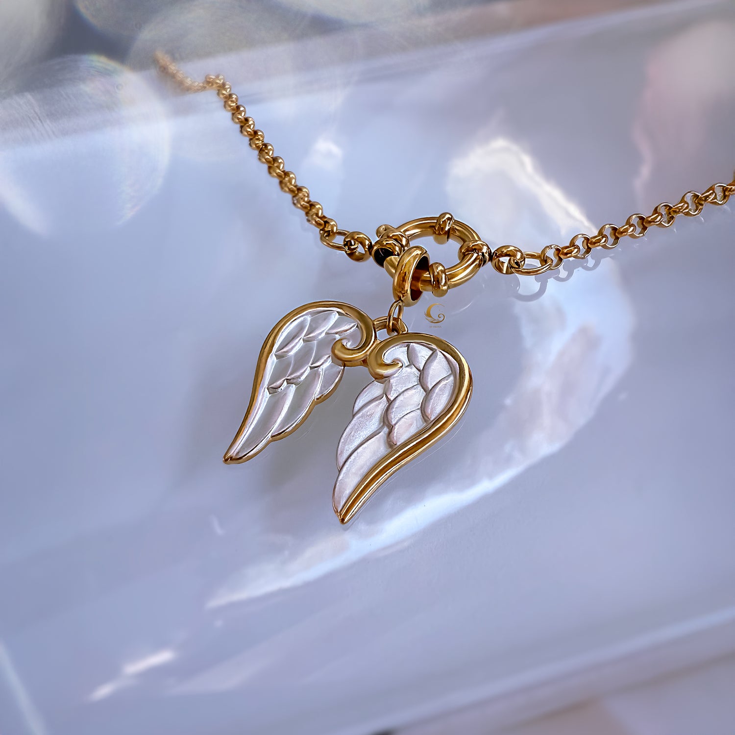 Gold and silver angel wing necklace on a white dish