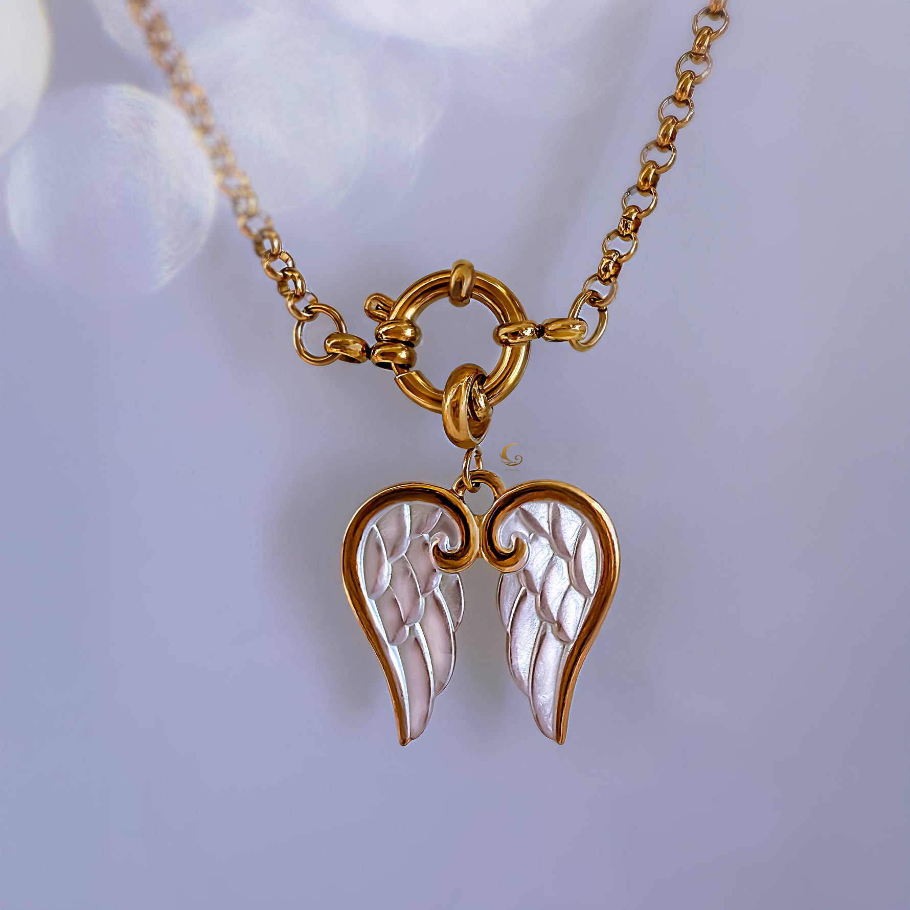 Gold necklace with angel wing pendant on a light background