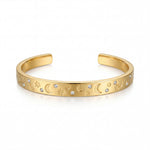 Gold bracelet with celestial designs on a white background