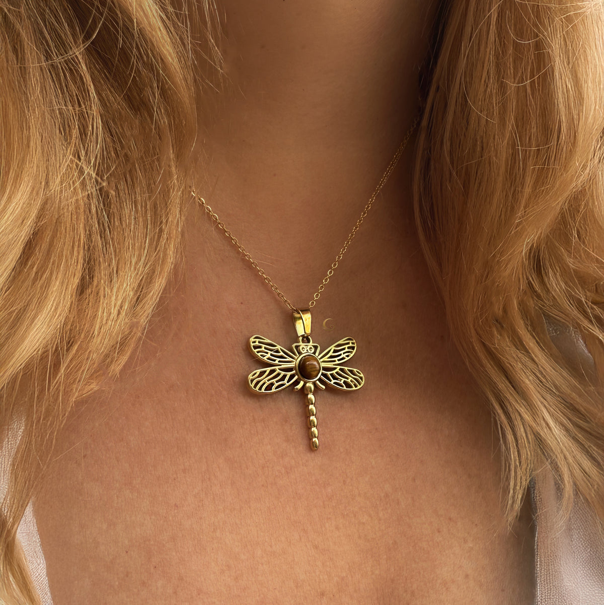 Gold dragonfly necklace on a person with blonde hair