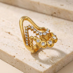 Gold ring with gemstones on a beige stone surface