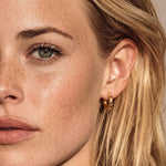 Close-up of a woman's face with blonde hair and a gold hoop earring.
