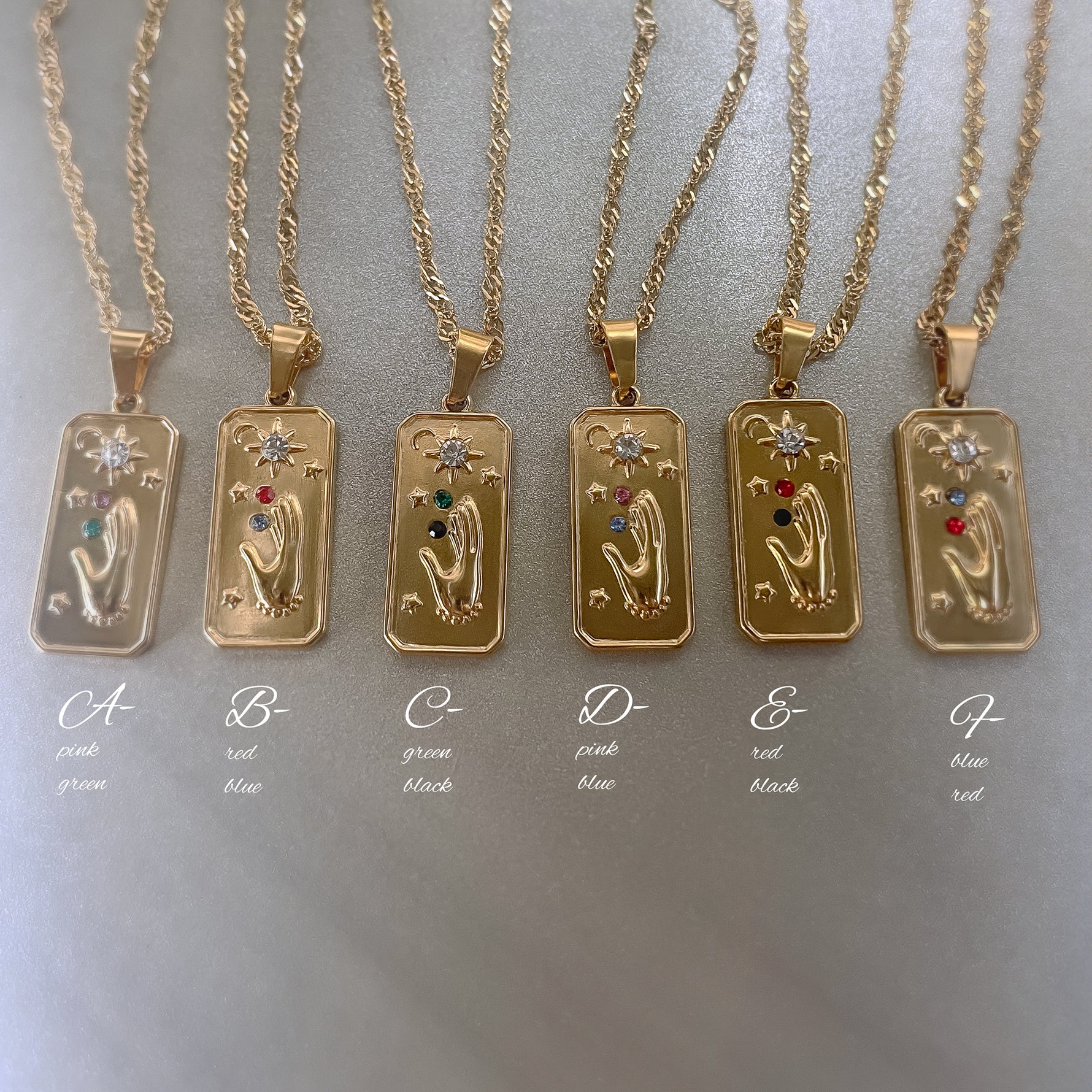 Gold necklaces with tarot card pendants on a gray background