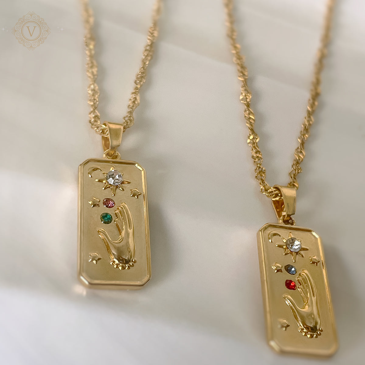 Two gold necklaces with pendant designs on a light background