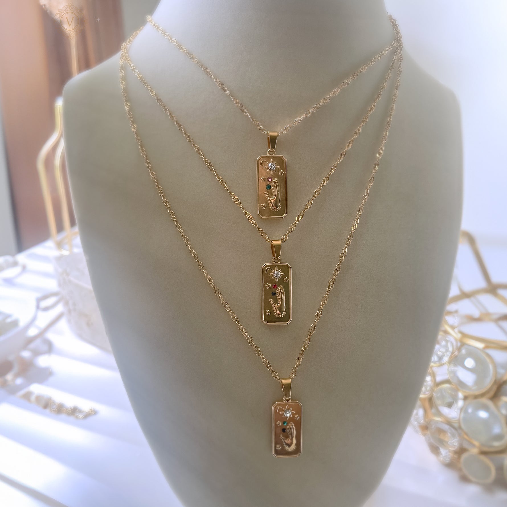 Three gold necklaces with rectangular pendants on a mannequin bust.