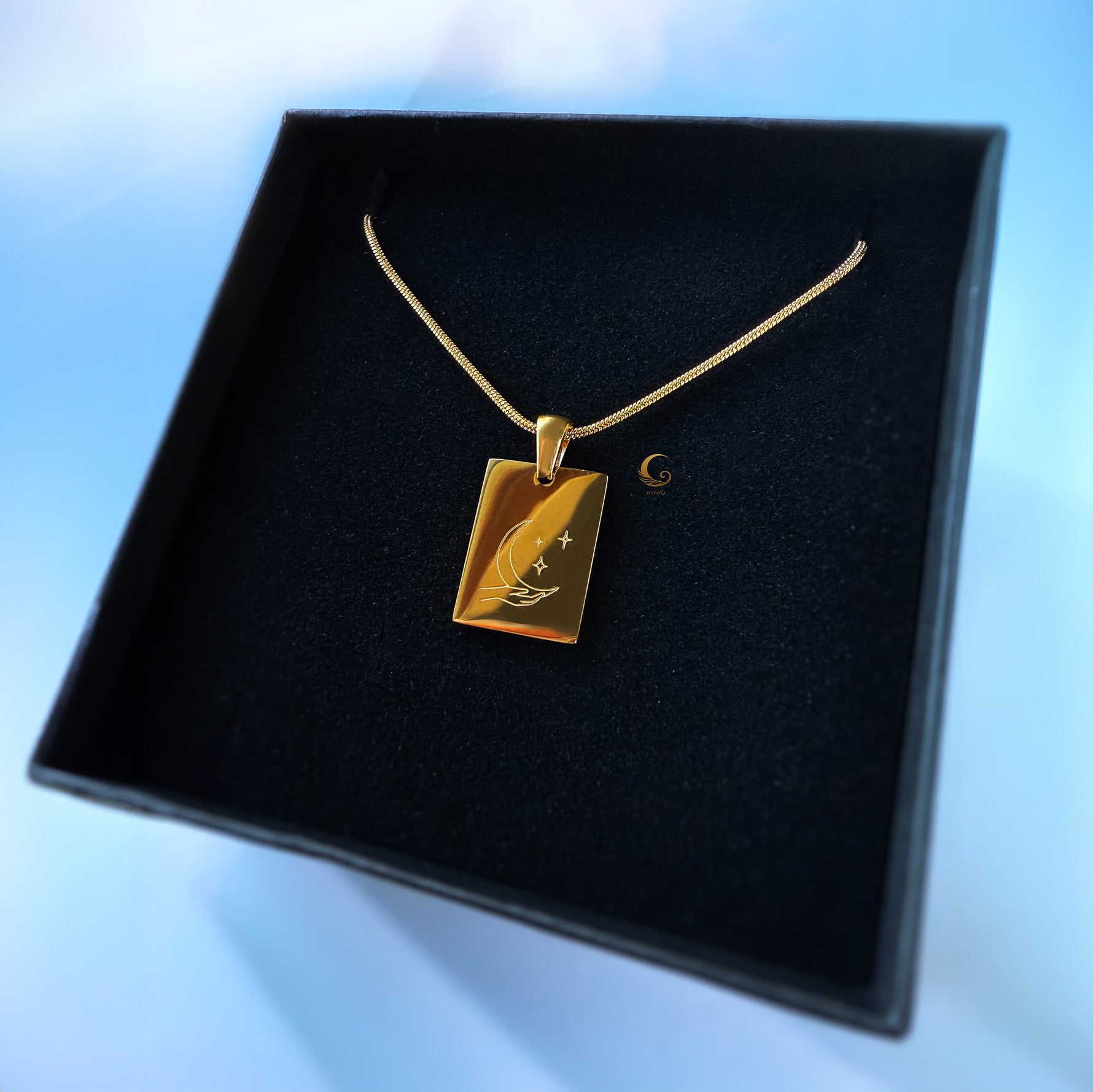 Gold necklace with a pendant on a black display box against a blue background