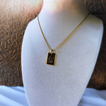 Gold necklace with a pendant on a mannequin bust against a neutral background