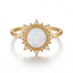 Gold ring with a central opal stone and diamond accents on a white background