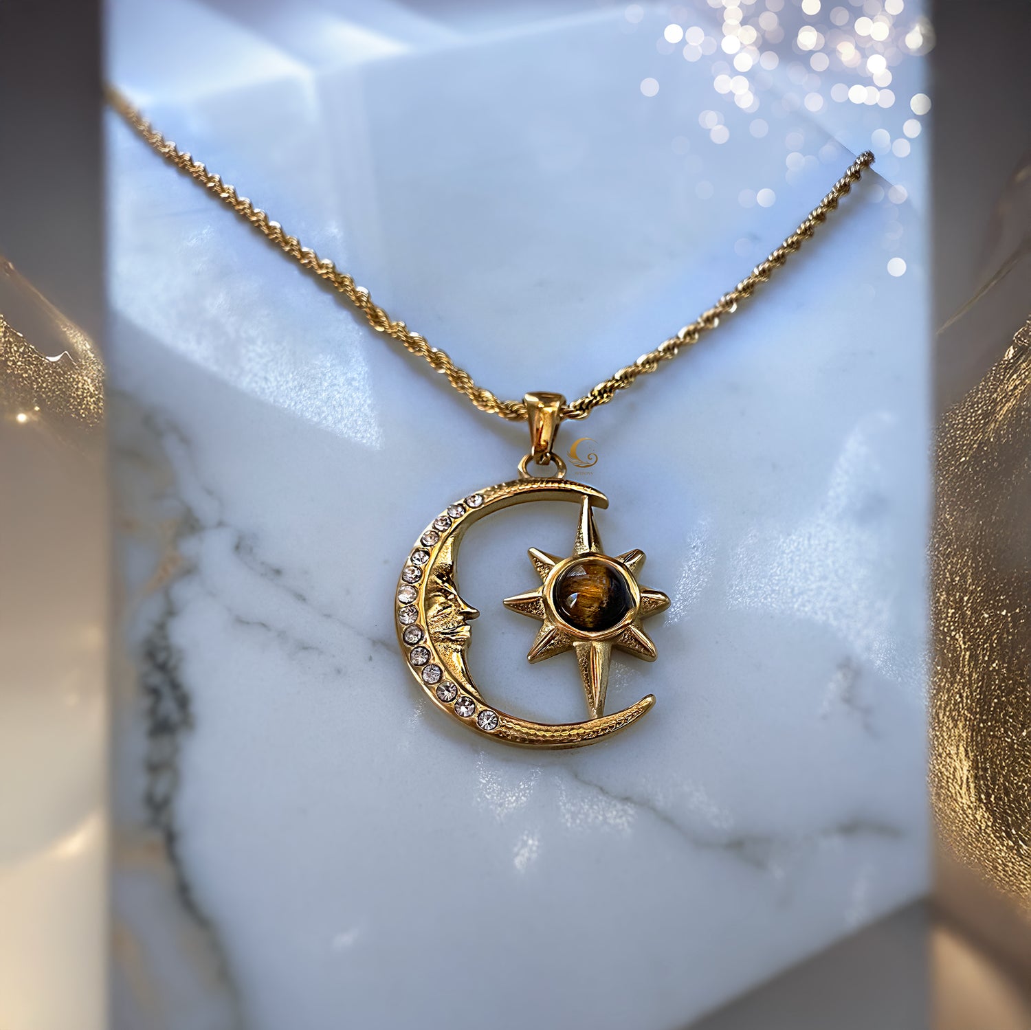 Gold necklace with a moon and sun pendant on a marble surface