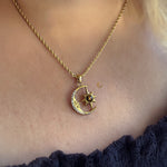 Gold necklace with a moon and star pendant on a person wearing a black top.