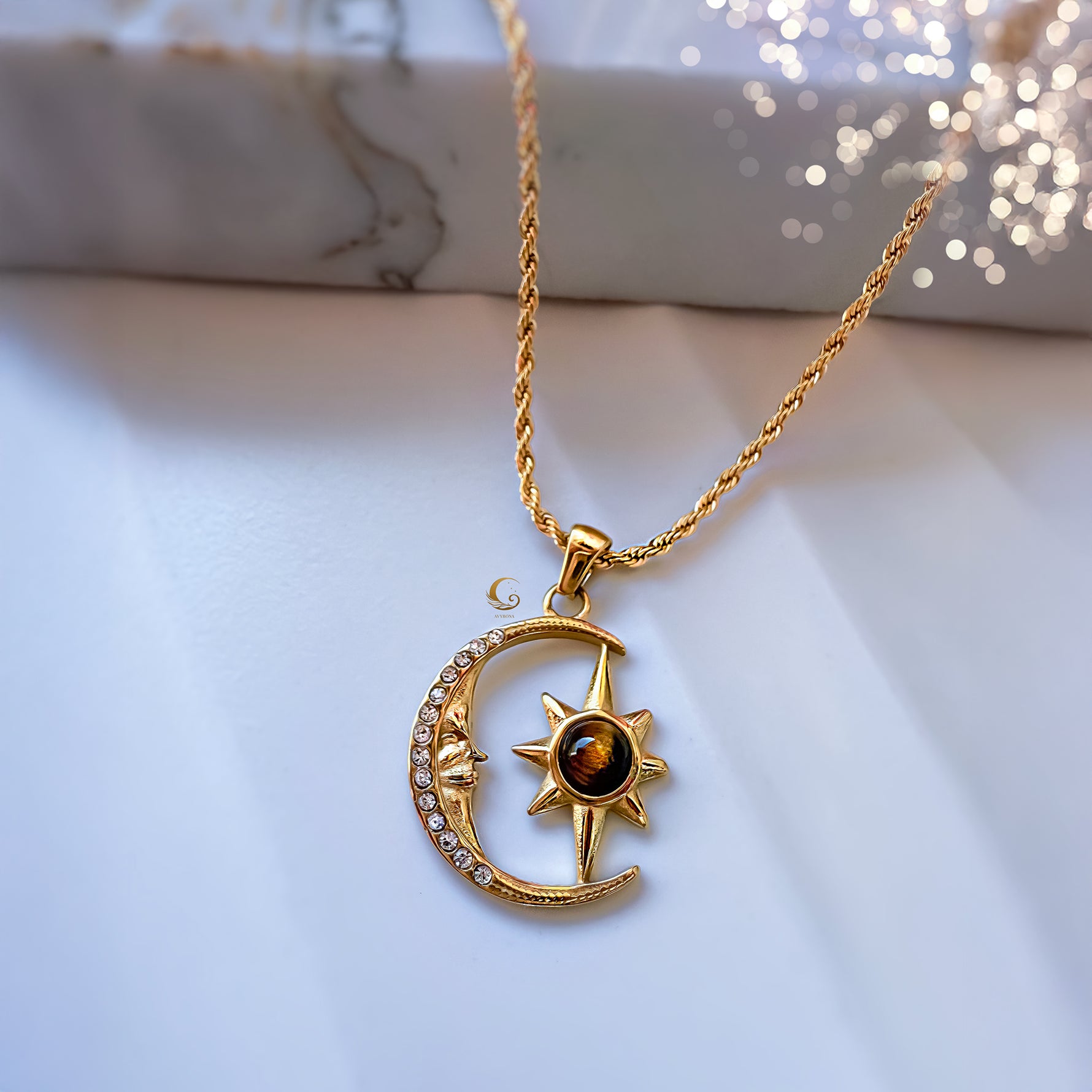 Gold necklace with a moon and star pendant on a marble surface