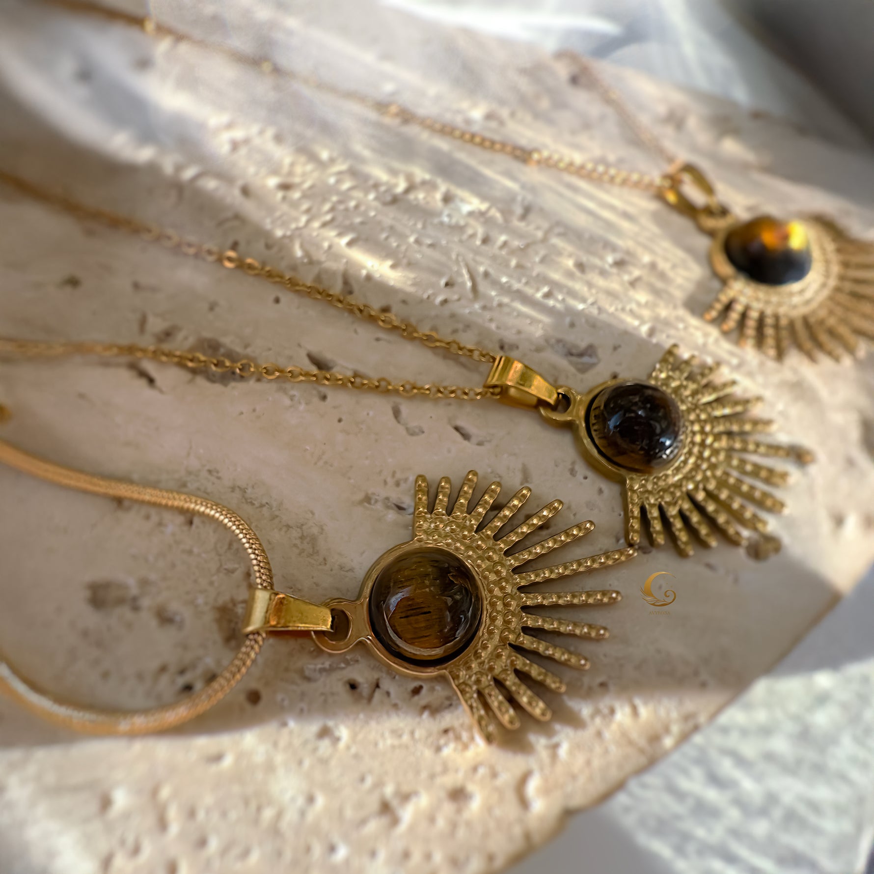 Gold necklaces with sunburst designs on a textured surface