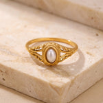 Gold ring with a pearl on a beige stone surface