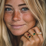 Close-up of a woman with freckles wearing multiple rings on her hand.