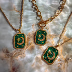Three green pendants with gold accents on a marble surface