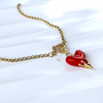 Fiery red heart necklace resting on white marble-like surface with soft shadows