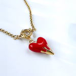 Macro shot of red enamel heart with golden flame-like tip and large rolo clasp
