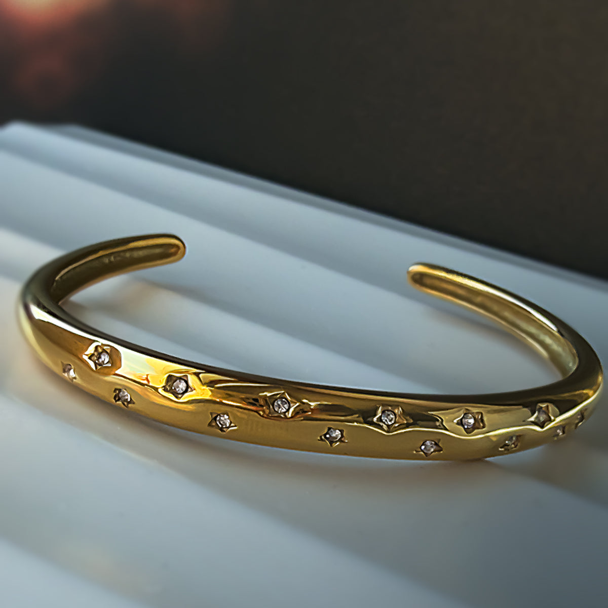 Frontal view of Aerina clear bracelet on white satin-like surface, highlighting star engravings.