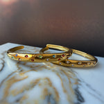 Flatlay of two Aerina bracelets – rainbow and clear versions – arranged on marbled background.