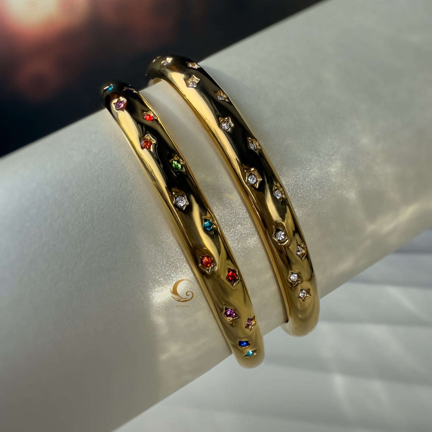 Side view of two Aerina bracelets showing star-shaped stone settings in rainbow and clear variations.