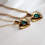 Close-up of heart-shaped emerald green crystal pendants on gold chains