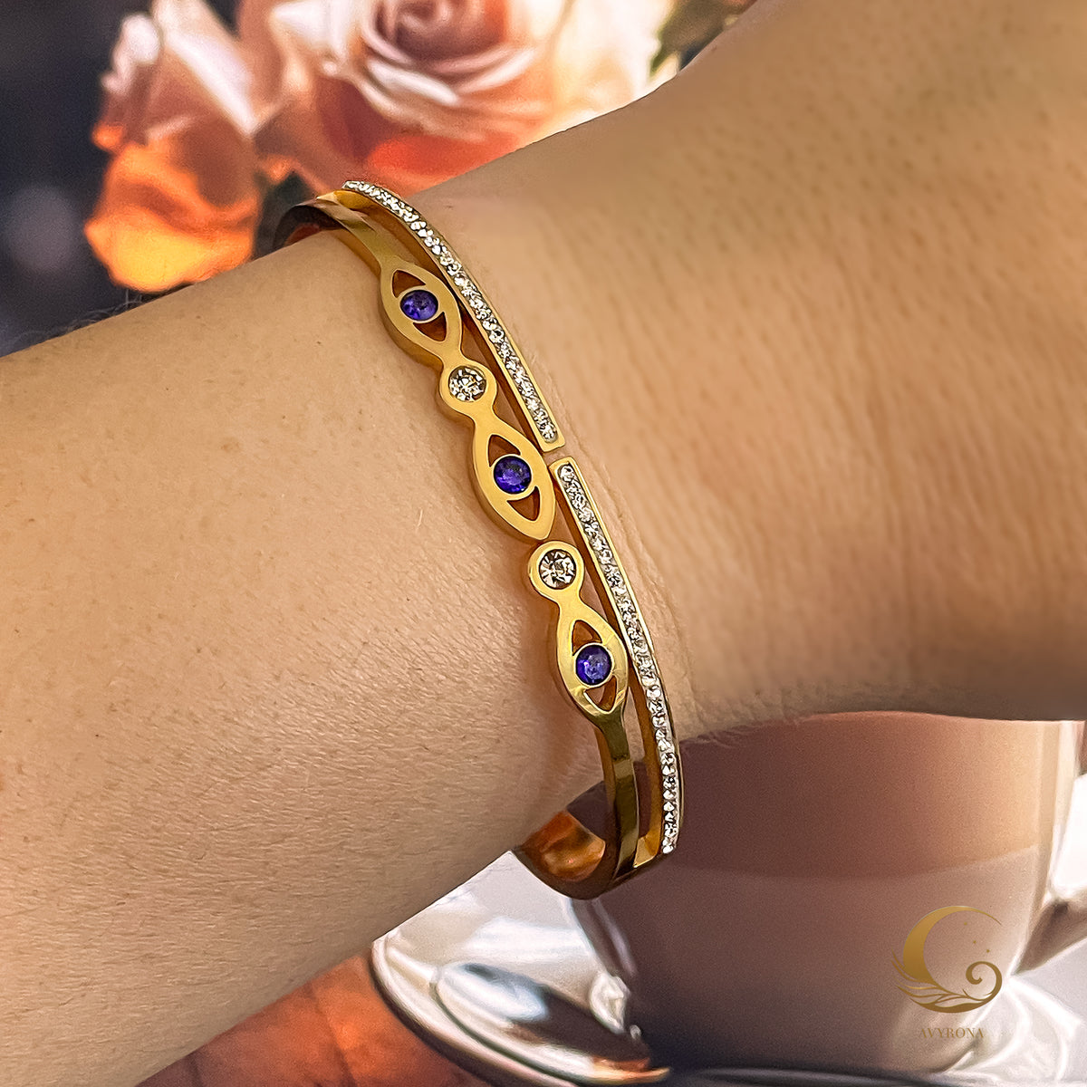 Aria gold bangle bracelet worn on wrist, showing navy Evil Eye and clear zirconia sparkle