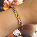 Aria gold bangle bracelet worn on wrist, showing navy Evil Eye and clear zirconia sparkle