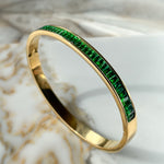 Side angle of emerald crystal bangle bracelet in golden tone, showcasing smooth finish and radiant shine