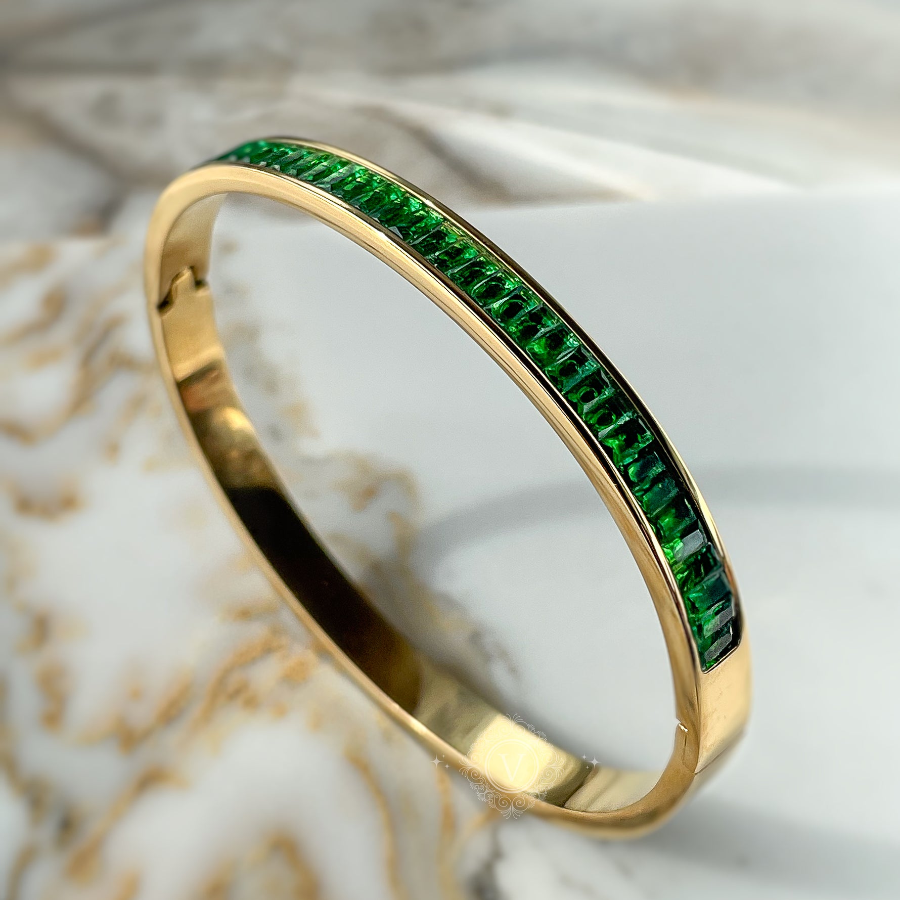 Side angle of emerald crystal bangle bracelet in golden tone, showcasing smooth finish and radiant shine