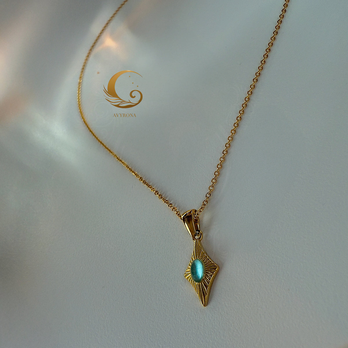 Single turquoise-blue cat eye charm necklace on smooth satin-like surface, minimal and elegant
