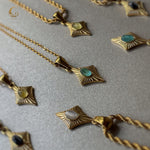 Flat lay of cat eye necklaces with different colored stones on a light textured surface, Avyrona collection