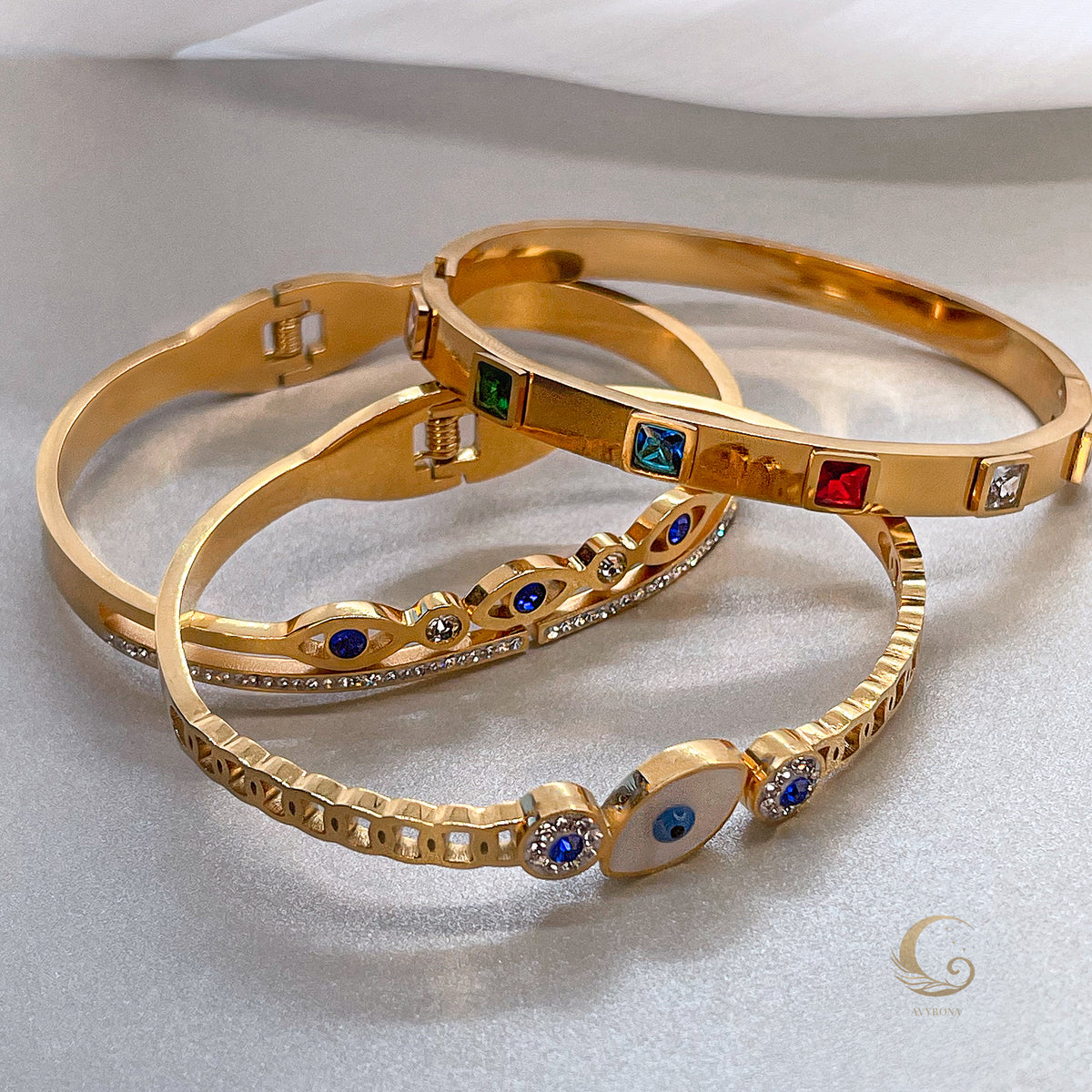 Stack of gold bracelets with colorful crystal bangle and evil eye design bangles, layered jewelry style – Avyrona