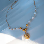 Side view of Ayla necklace highlighting pearl details and sun pendant in soft natural light.