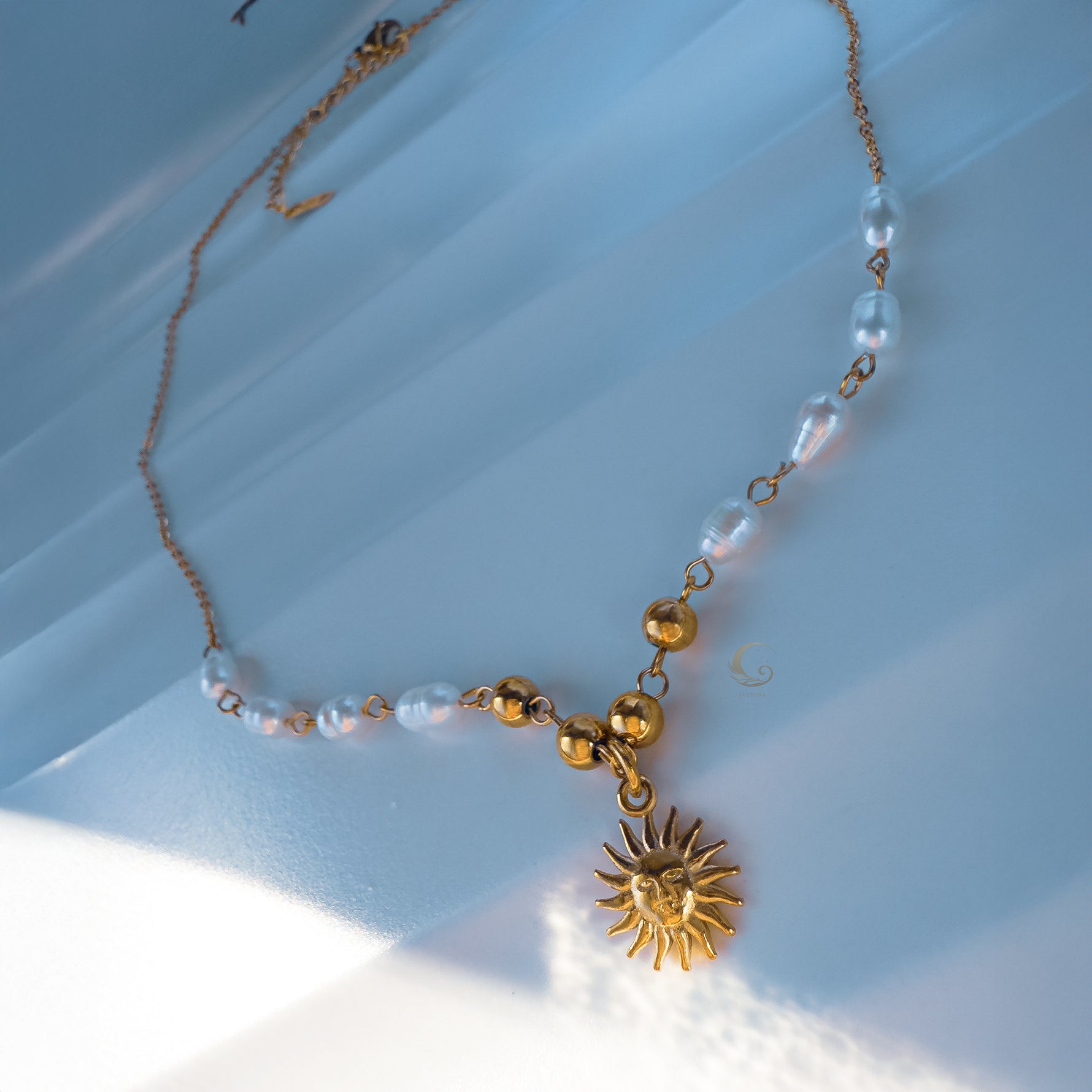Side view of Ayla necklace highlighting pearl details and sun pendant in soft natural light.