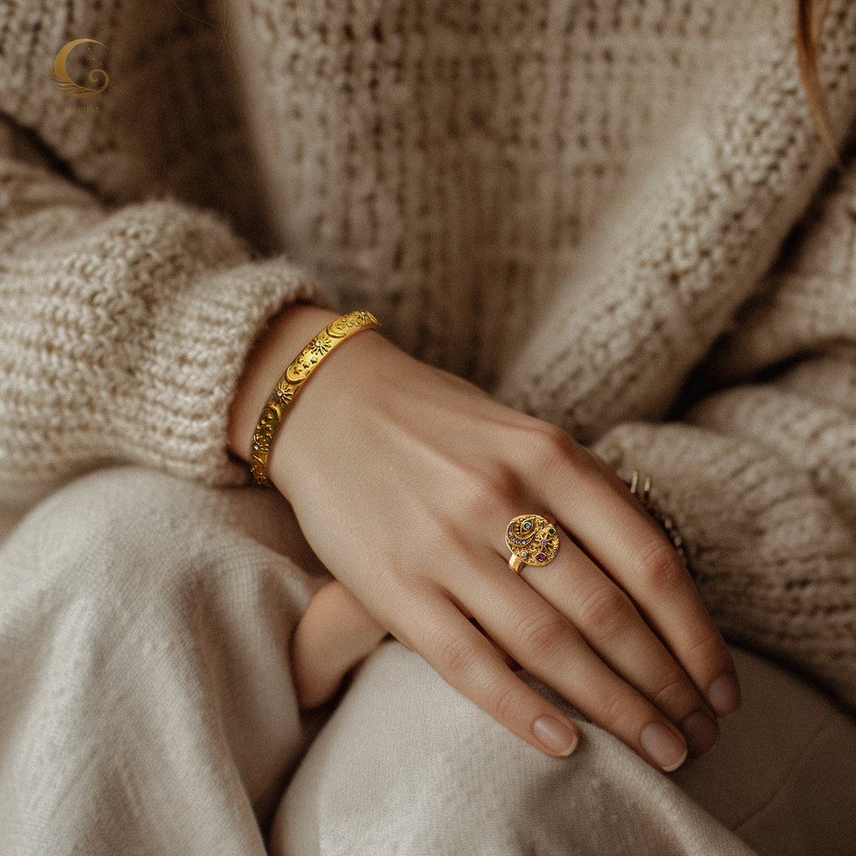 Lifestyle photo showing the bracelet worn on the wrist with a cozy knit sweater, paired with a matching gold statement ring.