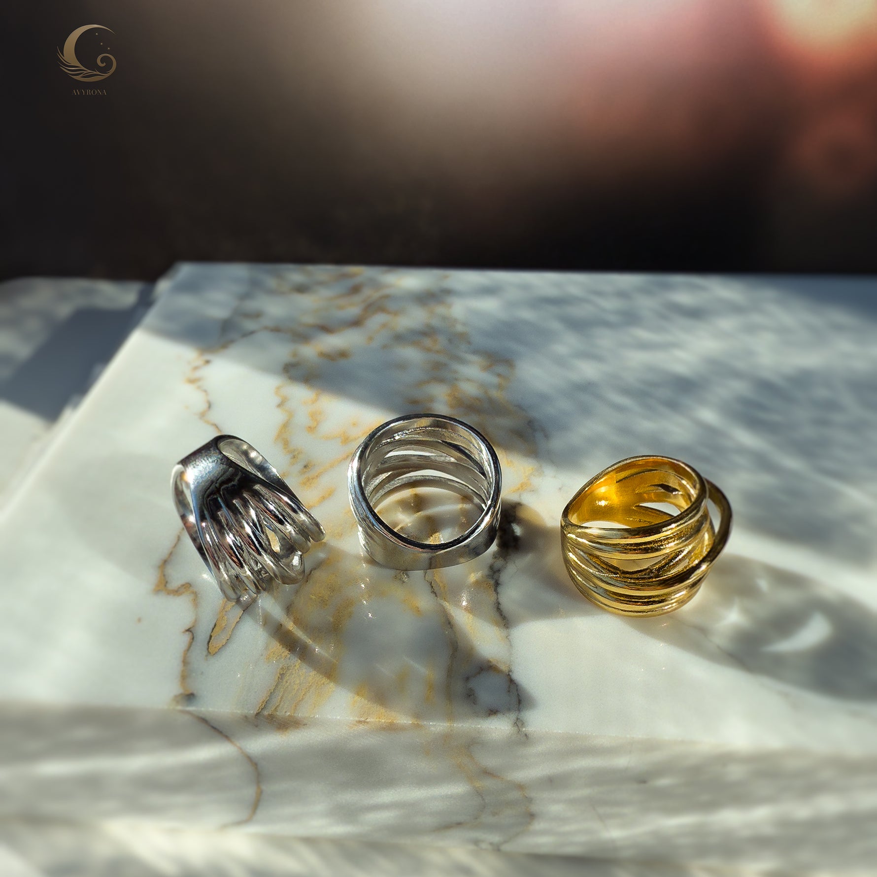 Top-down view of three Branch Rings placed on marble, showing off their natural texture and sculptural curves.