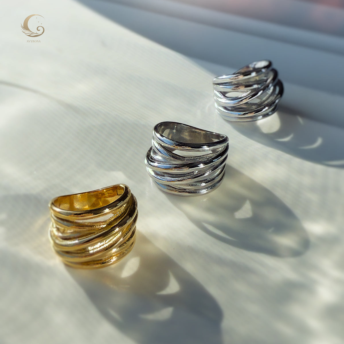 Close-up of the gold and silver Branch Rings lying on a light surface, showing their flowing, nature-inspired sculptural design.