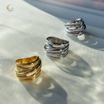 Close-up of the gold and silver Branch Rings lying on a light surface, showing their flowing, nature-inspired sculptural design.