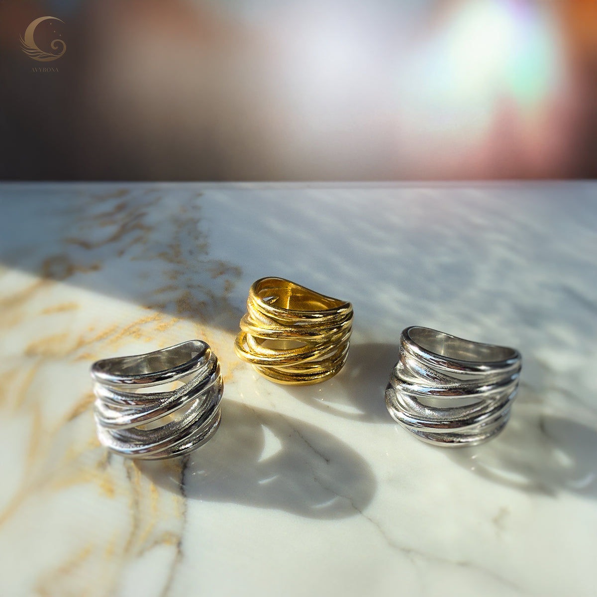 Trio of Branch Rings in gold and silver tones arranged on marble, reflecting their organic tree-branch texture.