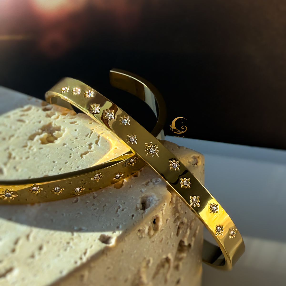 Two celestial bracelets with cubic zirconia captured at an angle, resting on stone in natural daylight.