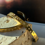 Two celestial bracelets with cubic zirconia captured at an angle, resting on stone in natural daylight.