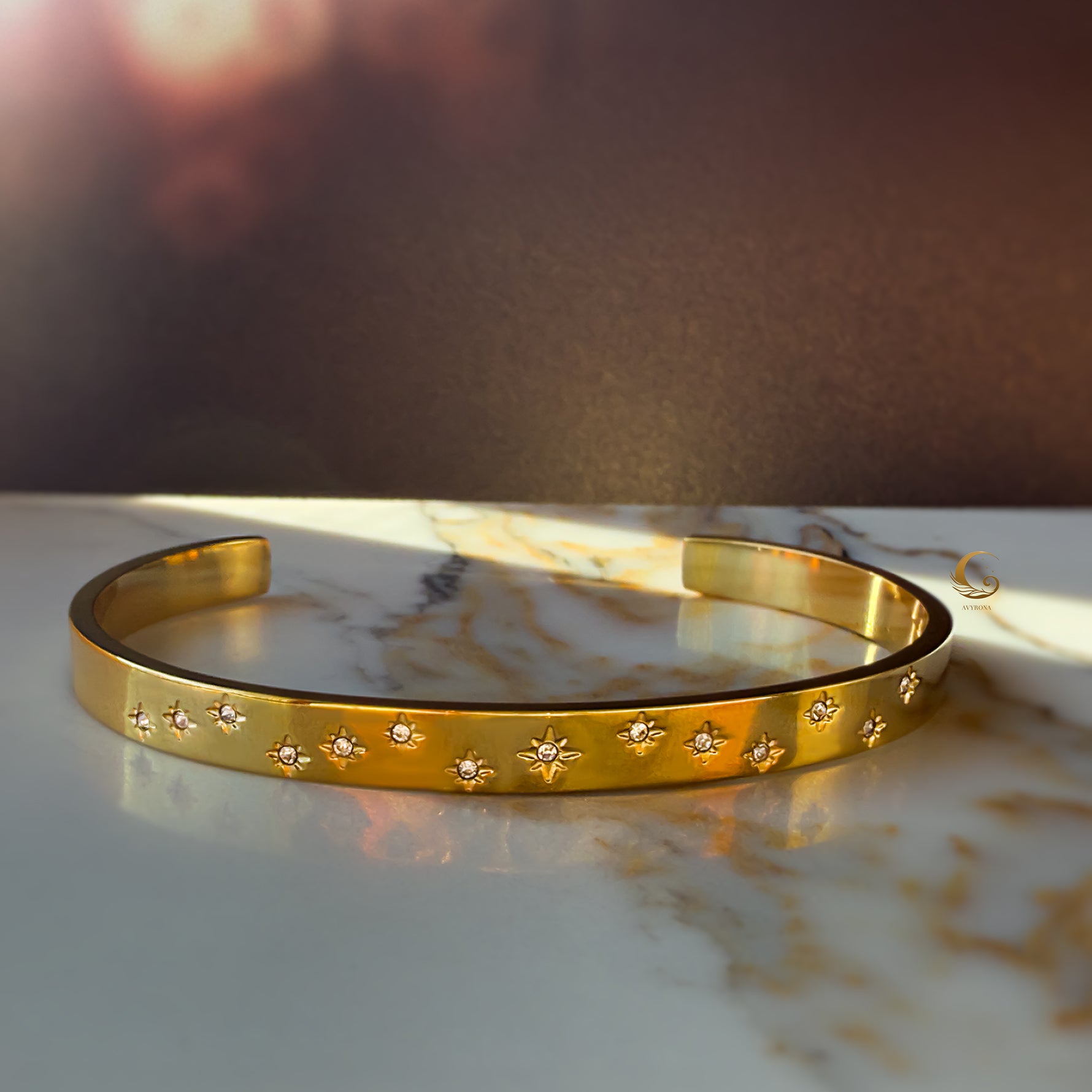 Minimalist gold bracelet styled with others in a layered stack on the wrist, showing variation of celestial designs.
