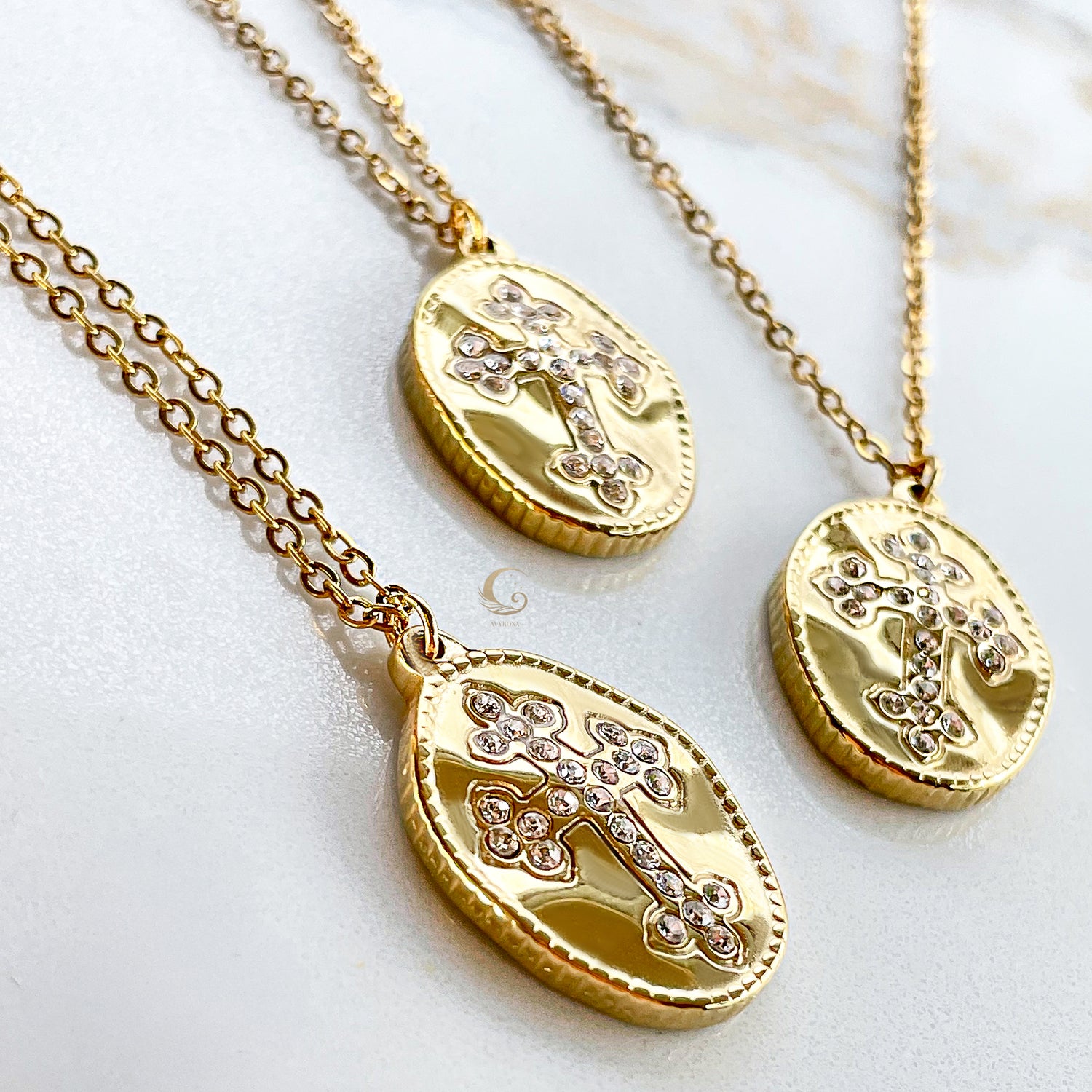 Close-up angled view showing the detailed craftsmanship of gold-plated cross necklaces with cubic zirconia on a marble background.