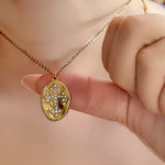 Celestia gold cross necklace gently held between fingers to show pendant size and sparkle against skin.