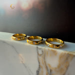 Three celestial rings with golden finish and cosmic symbols displayed on marble