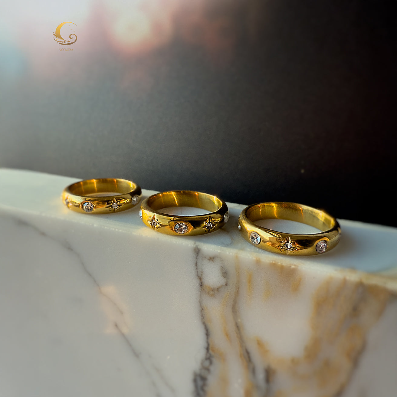 Three celestial rings with golden finish and cosmic symbols displayed on marble